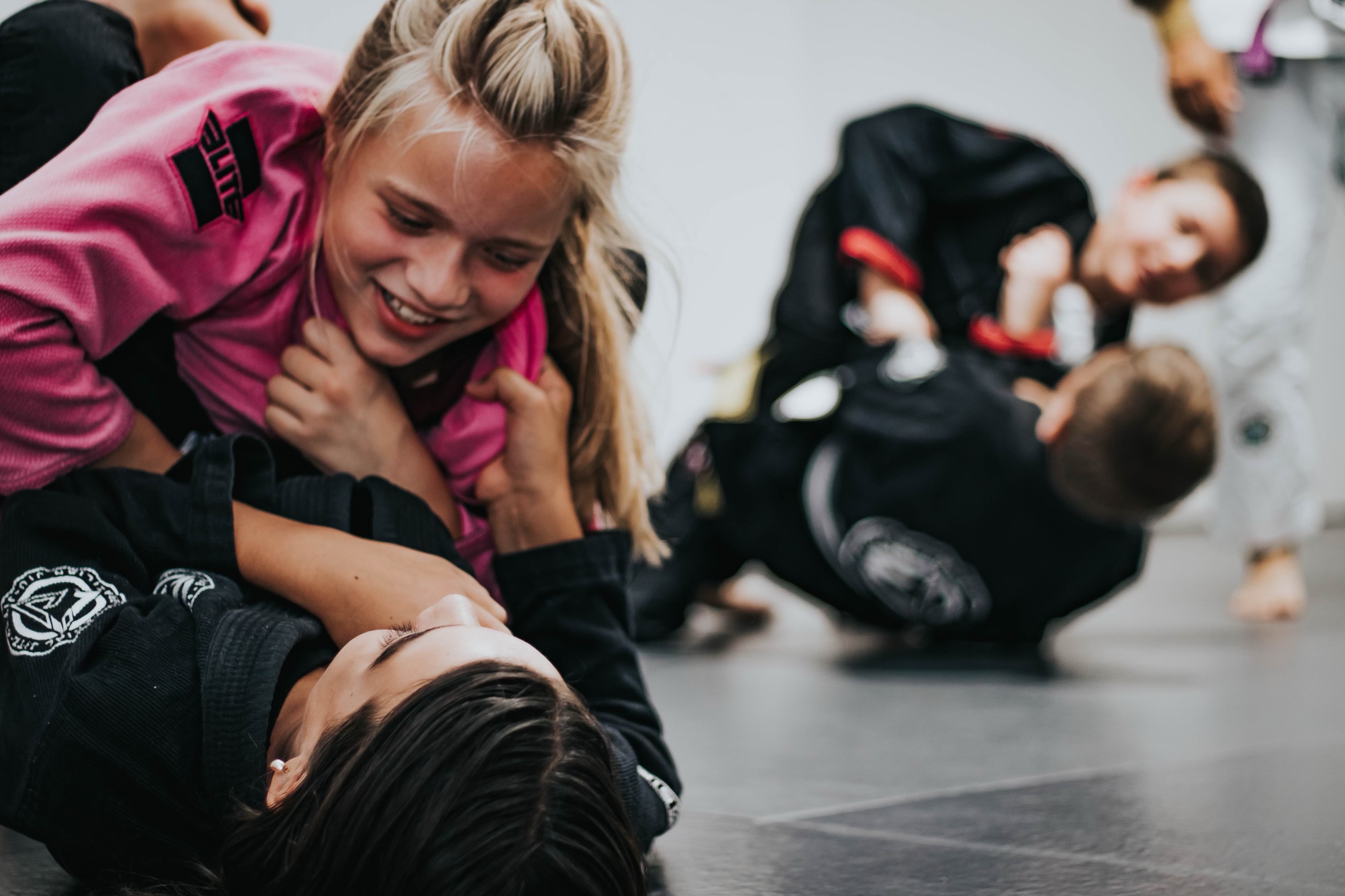youth students laughing while rolling (training jiu-jitsu a martial art of self-defense and self-offense)